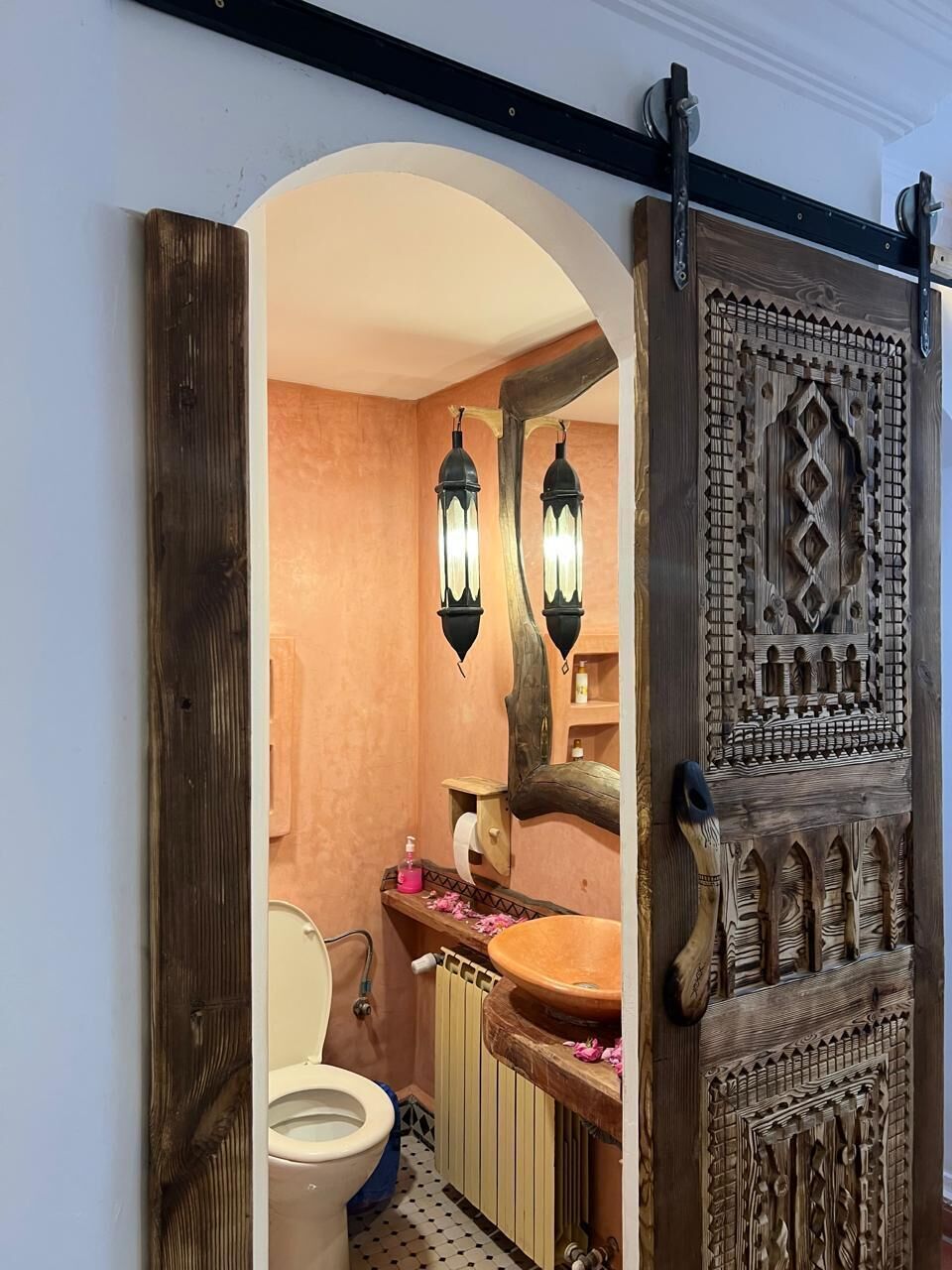 A bathroom with a wooden door, a toilet, and a sink.