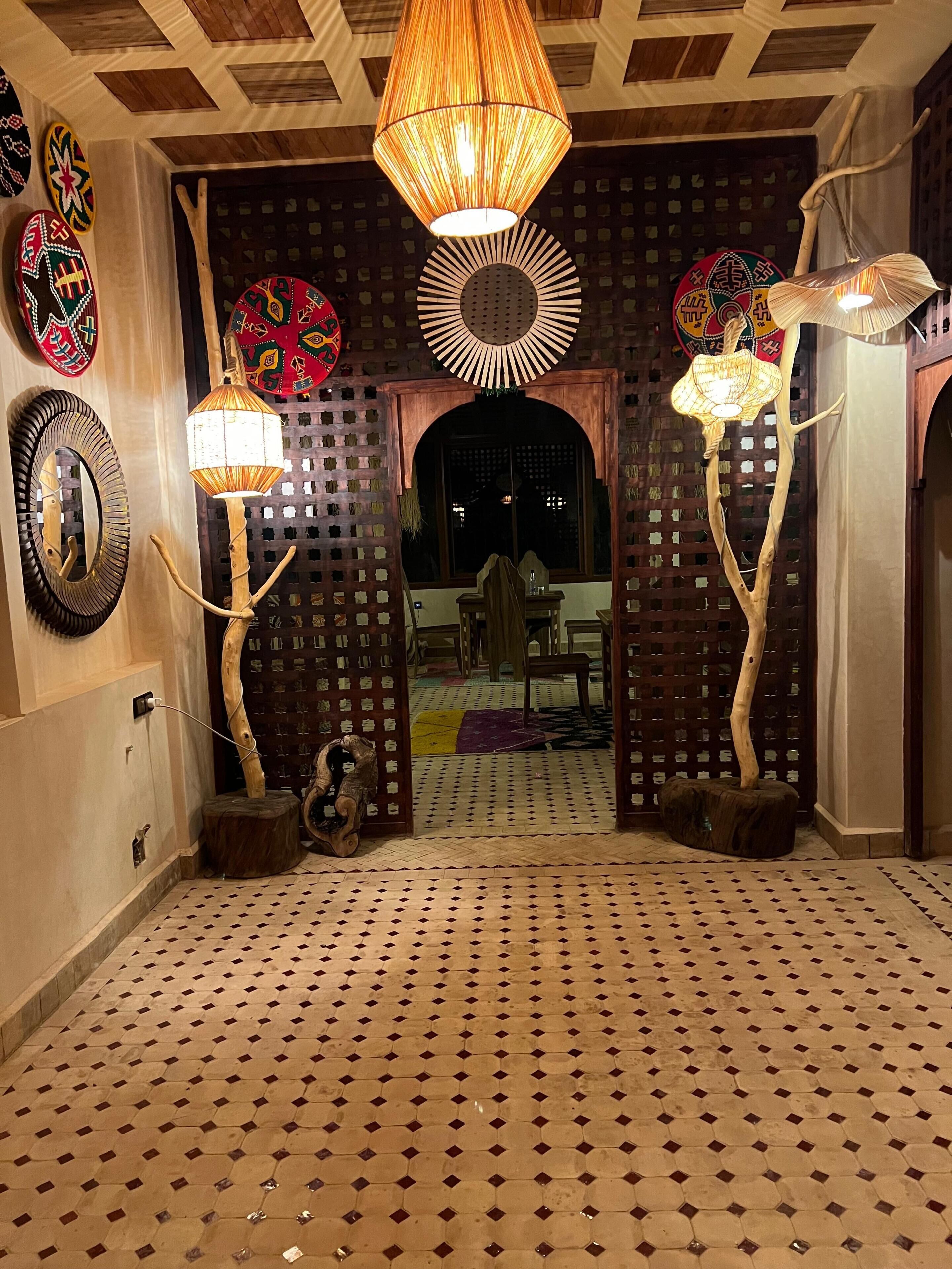 A room with a patterned floor, a wooden door with a lattice design, and a hanging lamp.