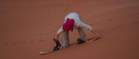 A person in white and red attire descending a sandy slope.