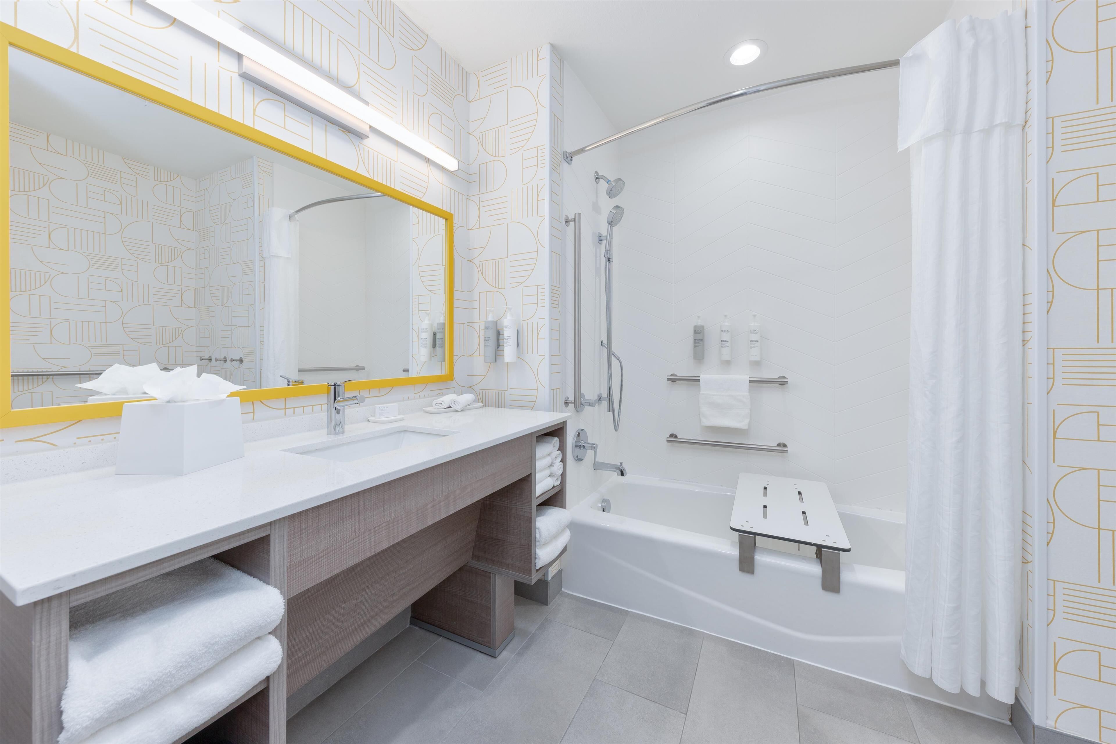 Un baño moderno con un espejo grande, lavamanos dobles, ducha y bañera.