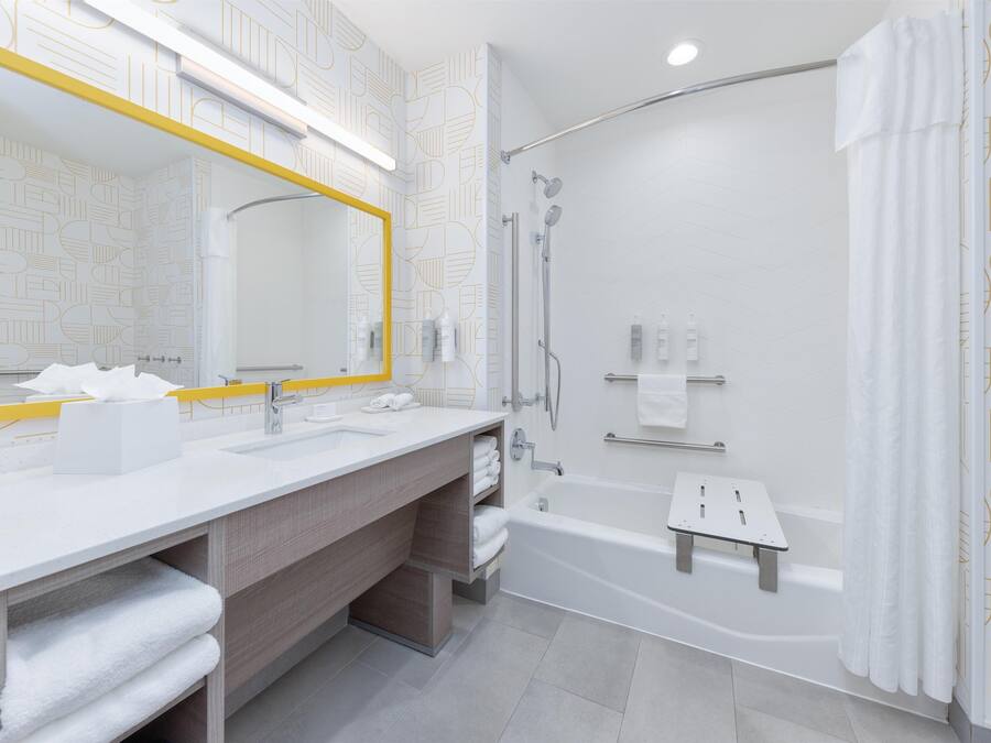 A modern bathroom with a large mirror, dual sinks, a shower, and a bathtub.