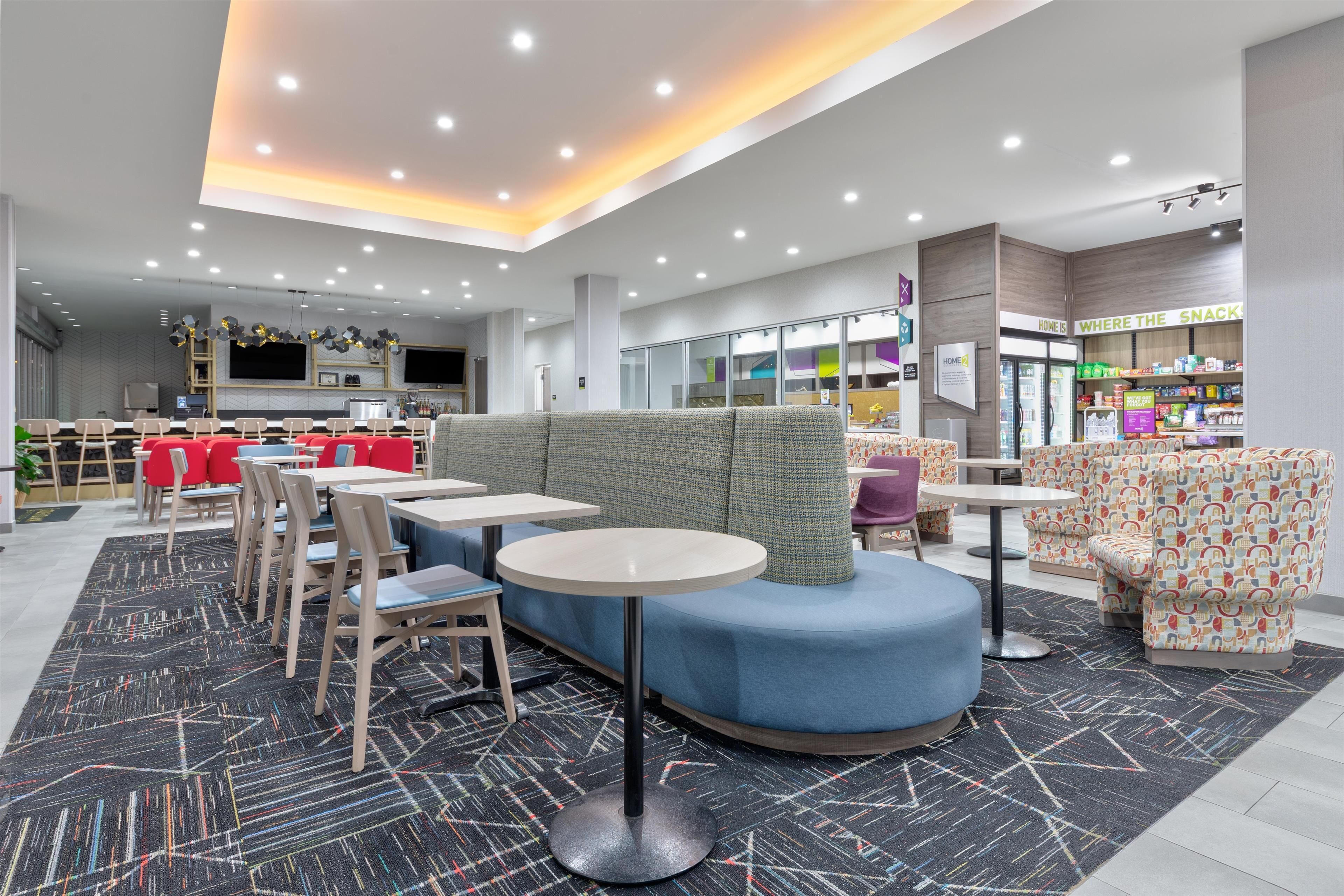 A modern cafe with round tables, red chairs, and a blue seating area.