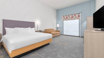 A hotel room with a bed, a desk, a chair, and a television.