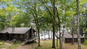 Une cabane dotée d’un porche et d’une petite terrasse, entourée d’arbres.