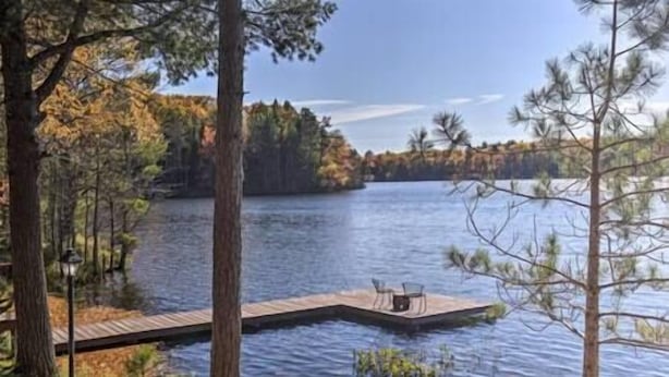 Une jetée s’avançant dans un lac paisible, bordé d’arbres.