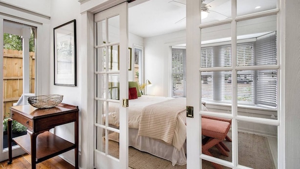 Un dormitorio con cama, mesita de noche y ventana con persianas.