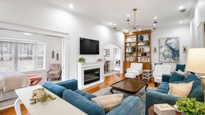 Una sala de estar moderna con chimenea, sofás azules, una mesa de centro y una estantería.