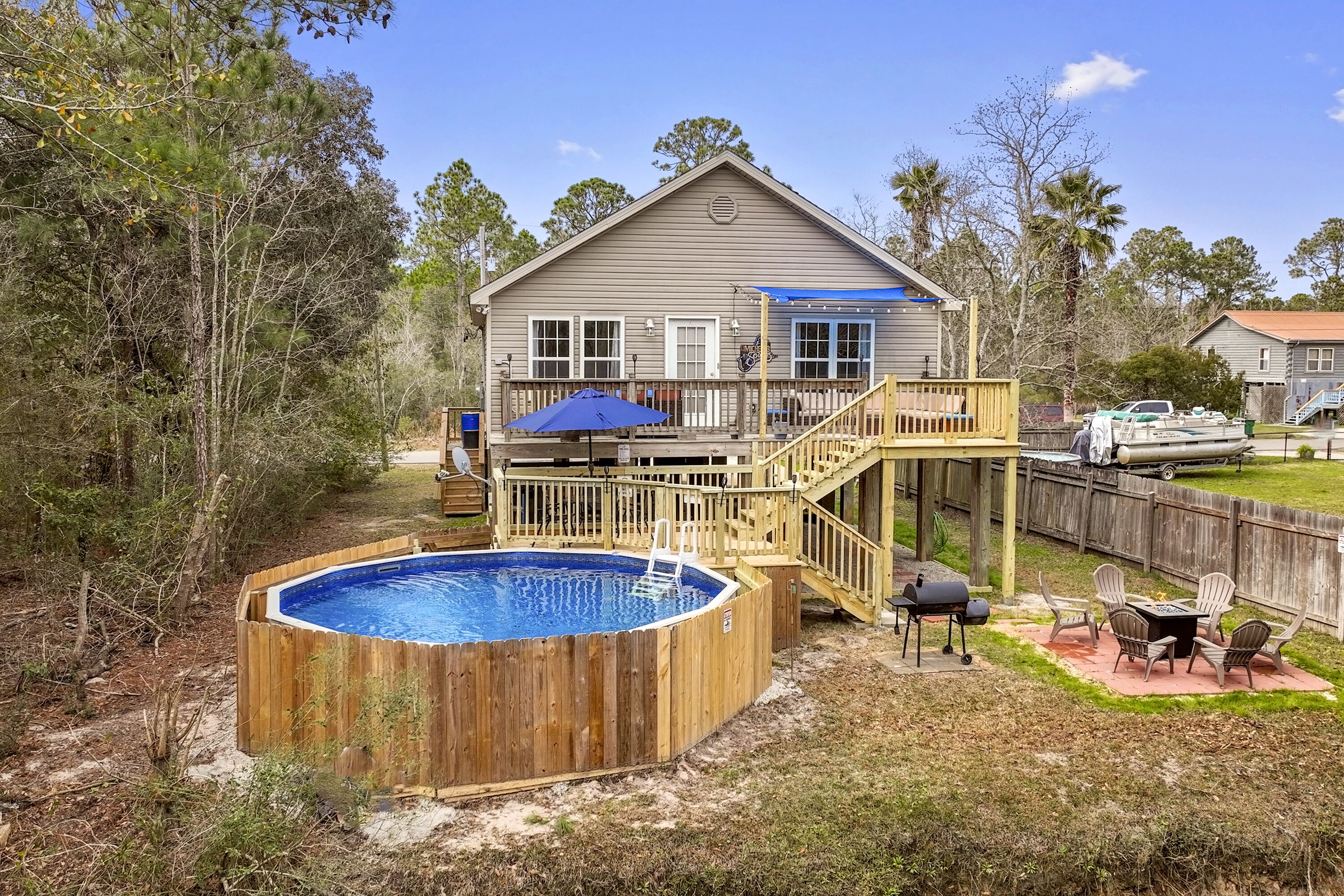Une maison dotée d’une terrasse en bois, d’un jacuzzi et d’un espace barbecue.