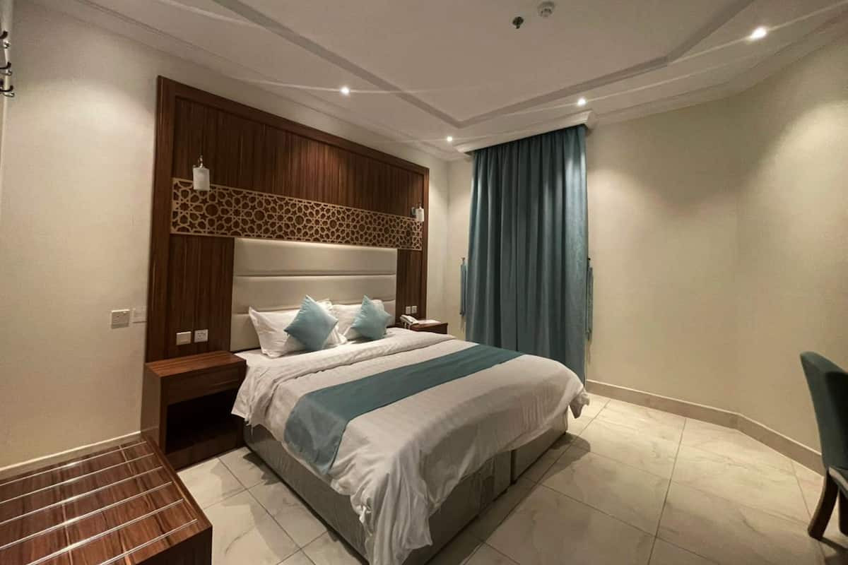 A modern bedroom with a large bed, wooden headboard, and a decorative wall panel.