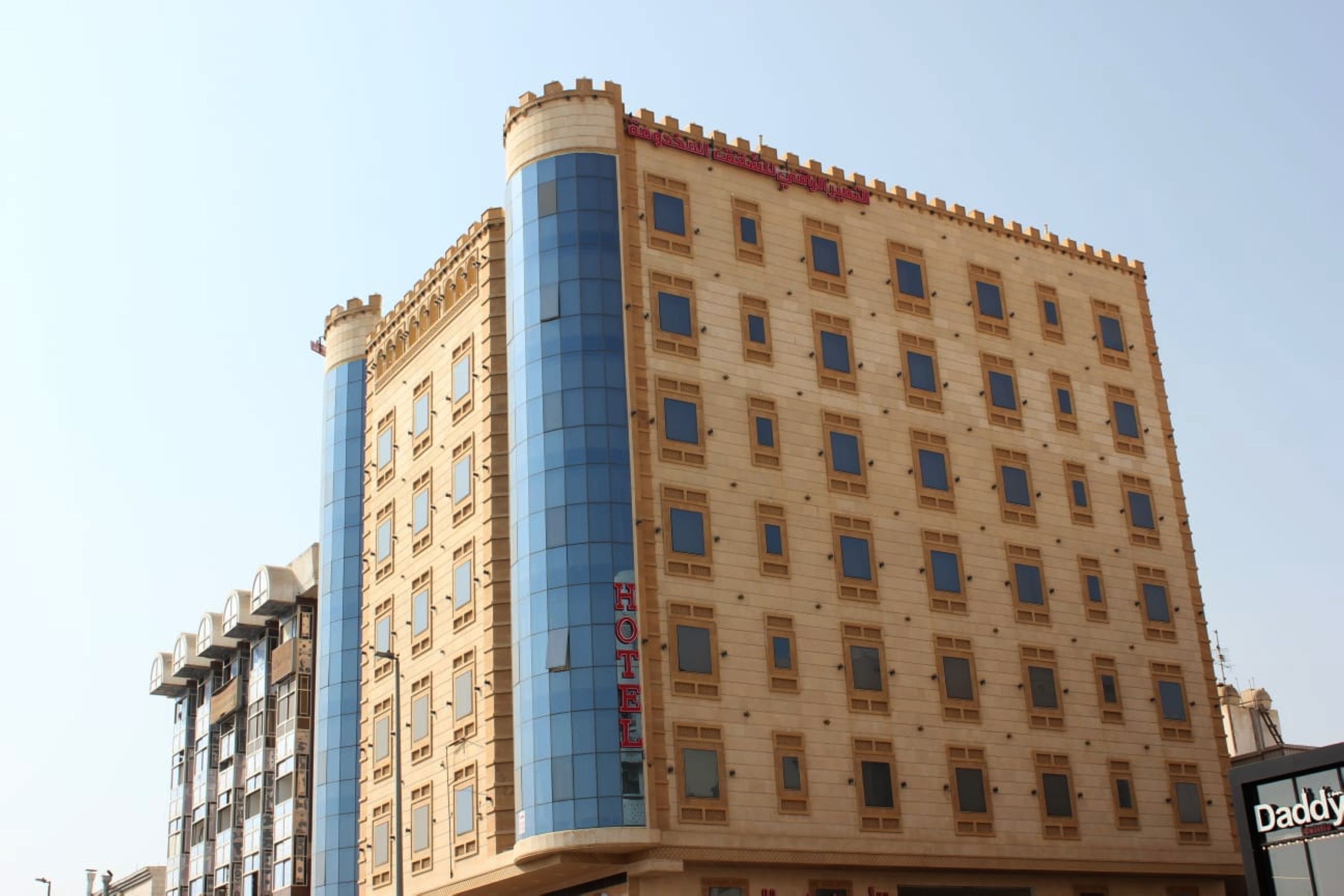Un hotel con fachada moderna, que destaca por un eje de ascensor de vidrio azul y un diseño clásico con amplias ventanas.