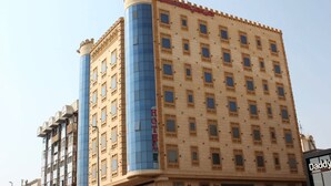A hotel with a modern facade, featuring a prominent blue glass elevator shaft and a classic design with multiple windows.