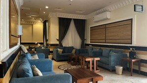 A modern living area with blue sofas, a wooden coffee table, and a large wall-mounted TV.