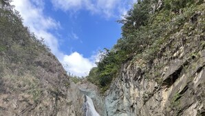 Una cascada se precipita sobre un risco rocoso hacia un río tranquilo.