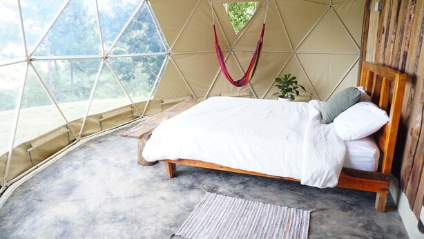 Un dormitorio acogedor tipo tienda de campaña, con cama y hamaca, y vistas al exterior.