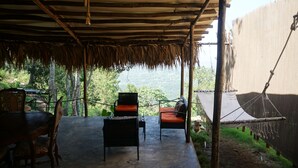 Un espacio de estar al aire libre cubierto con sillas y una mesa, con vista a un paisaje natural.