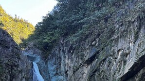Una cascada en un desfiladero rocoso, con un primer plano de piedras pequeñas.