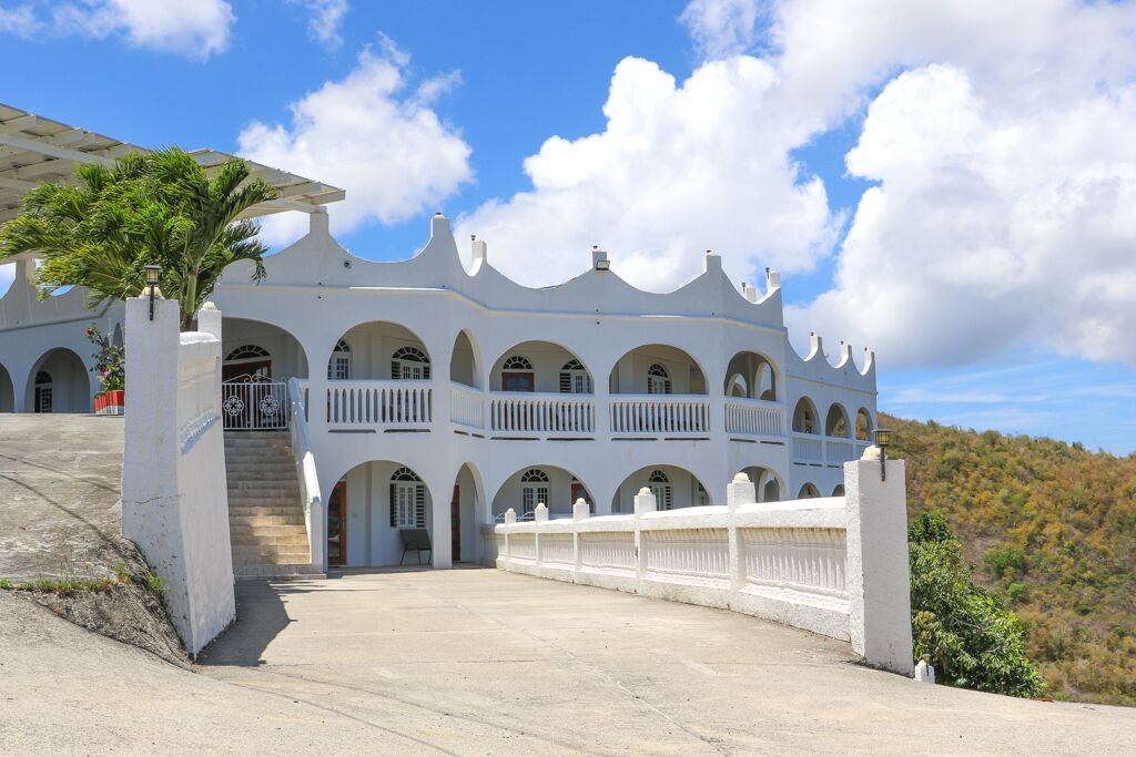 A white building with multiple balconies and arched windows, featuring a central staircase leading to an upper level.