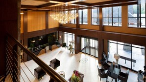 A spacious lobby with a high ceiling, large windows, and a modern chandelier.