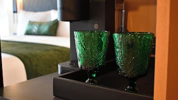 Quarto de hotel com uma cama, uma cafeteira e dois copos verdes em um tabuleiro.