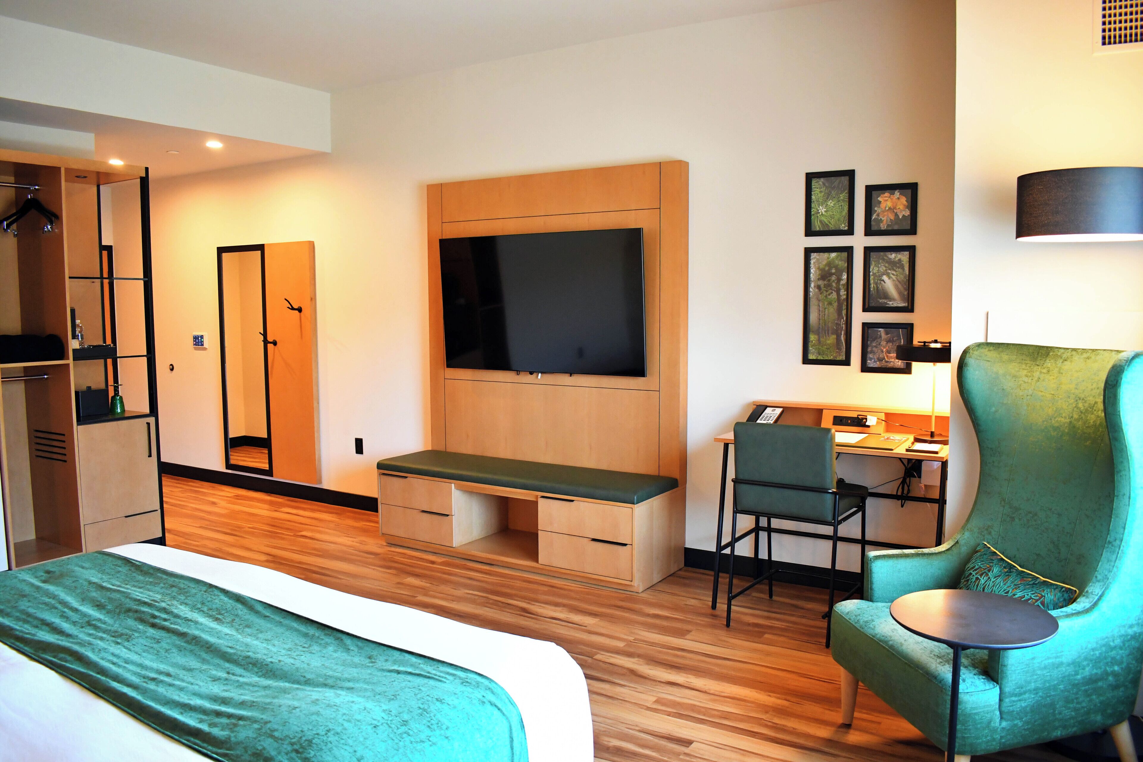Habitación de hotel con cama, escritorio, silla, televisor y armario.
