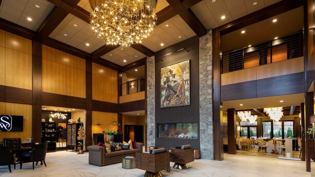 A spacious lobby with a grand chandelier, a fireplace, and a large painting on the wall.