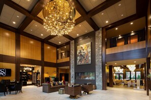 A spacious lobby with a grand chandelier, a fireplace, and a large painting on the wall.