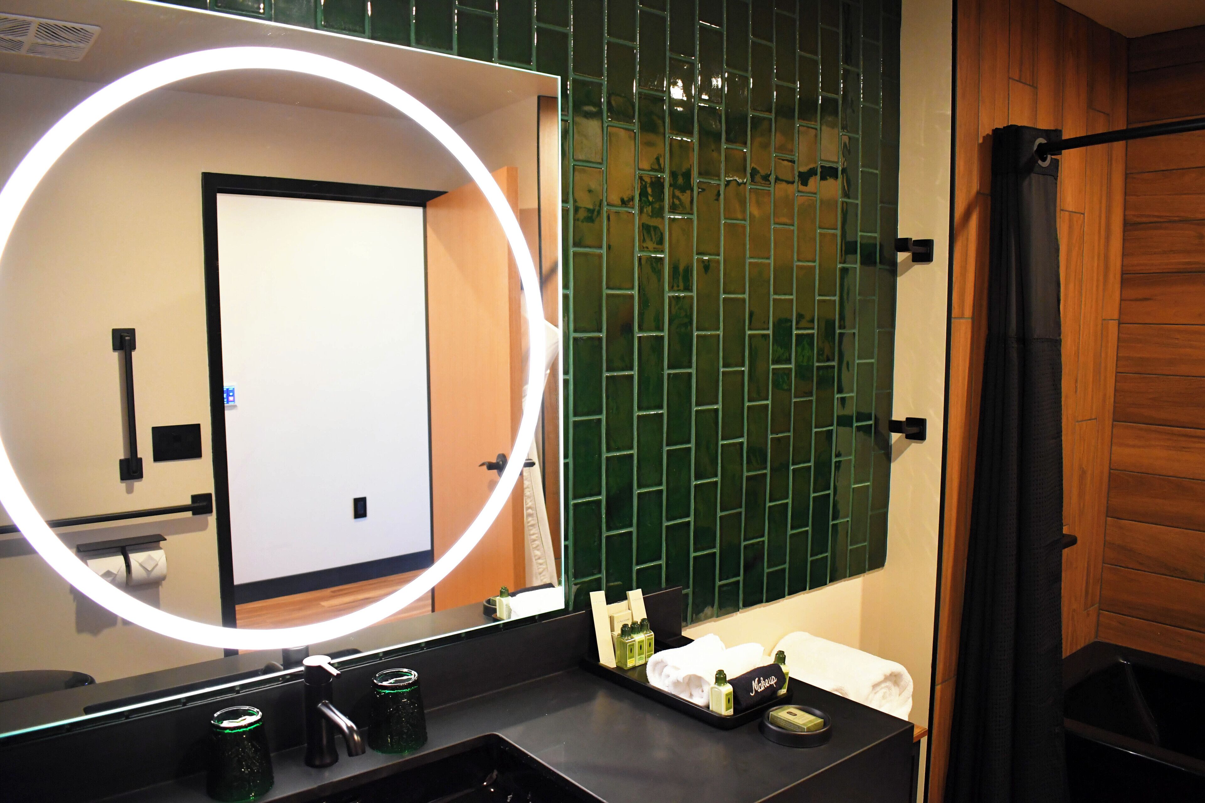 A bathroom with a mirror, a sink, and a shower area.