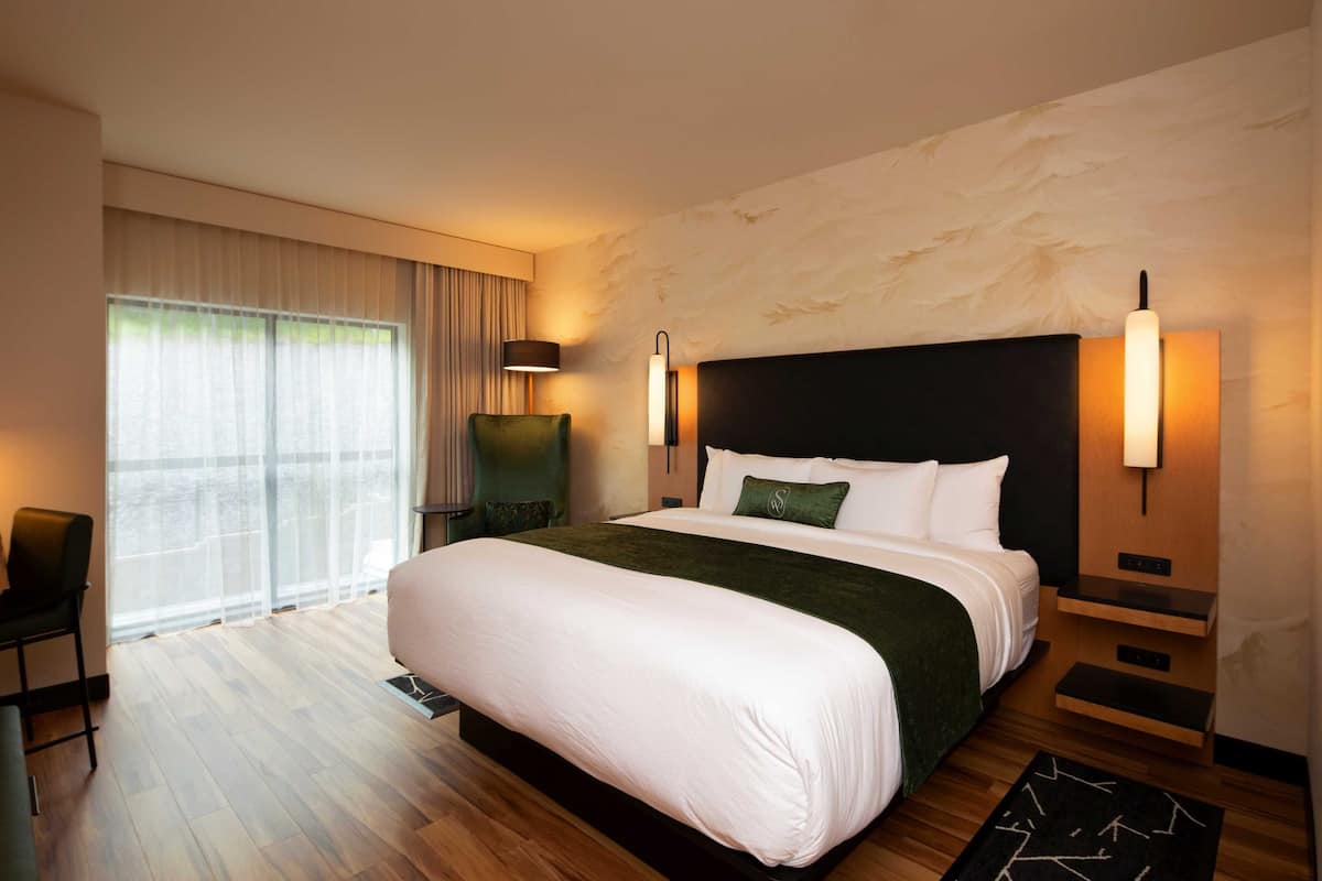 A modern hotel room with a large bed, a desk, and a chair.