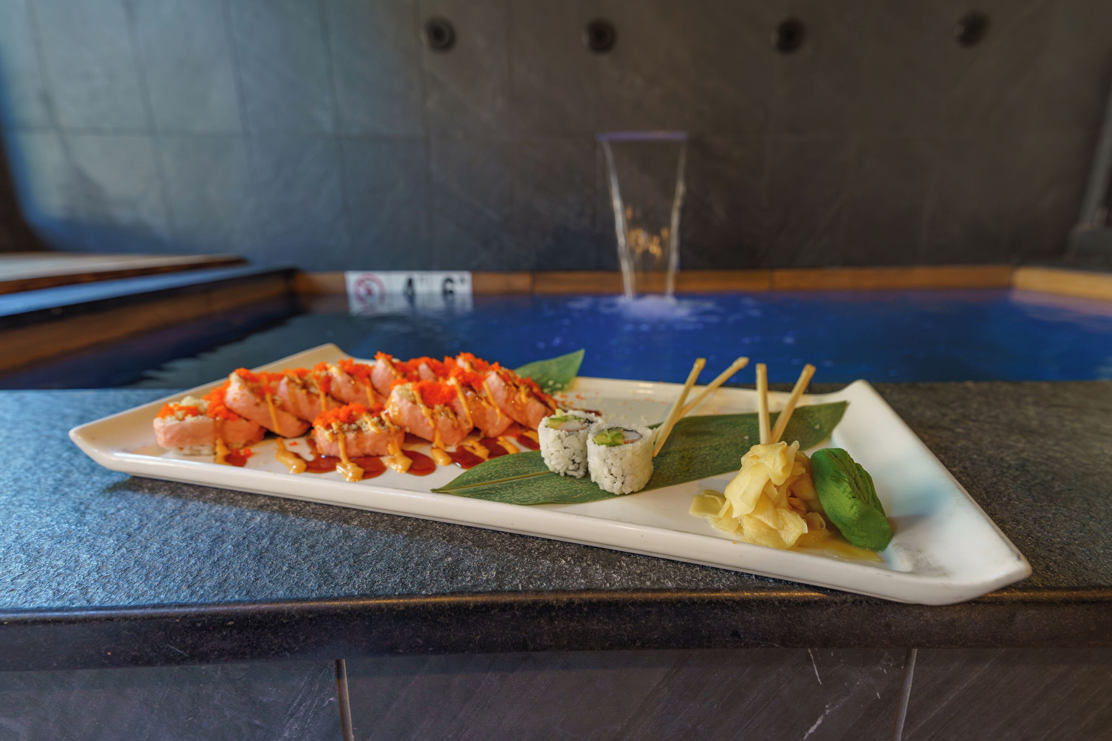 Un plato de sushi sobre una mesa oscura, con diversos rollos y nigiri.