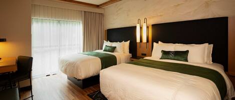 A hotel room with two beds, a desk, and a chair.