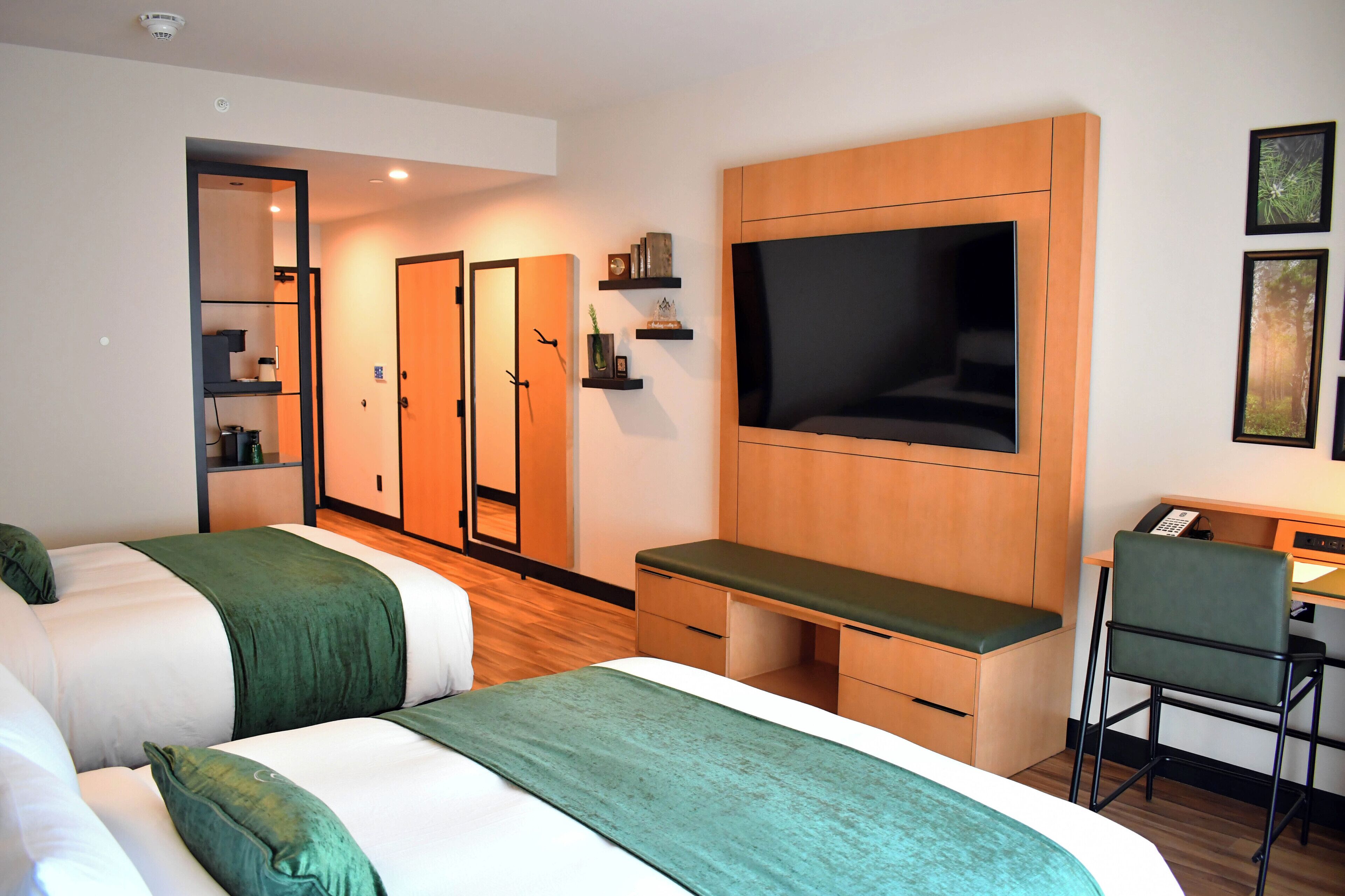 Habitación de hotel con dos camas, un escritorio con silla, televisor y armario.