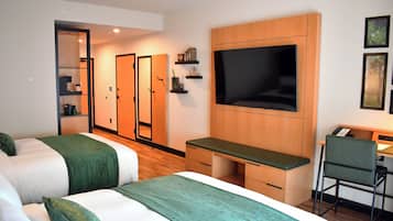 Habitación de hotel con dos camas, un escritorio con silla, televisor y armario.