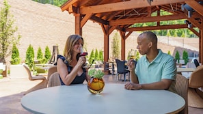 Relax in a serene outdoor setting with a round table and wicker chairs under a pergola.