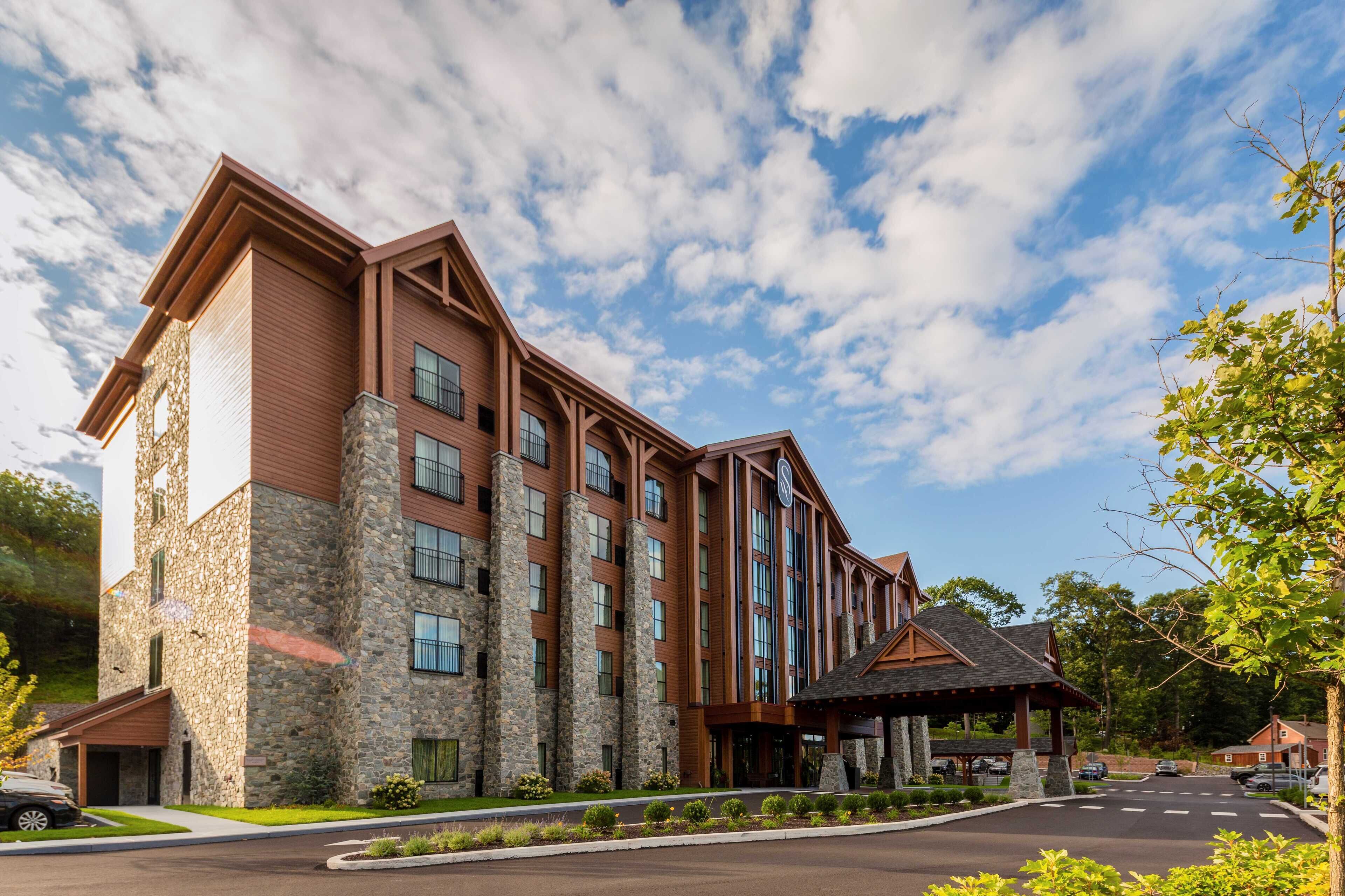 A multi-story hotel with stone and wood exterior, large windows, and a covered entrance area.