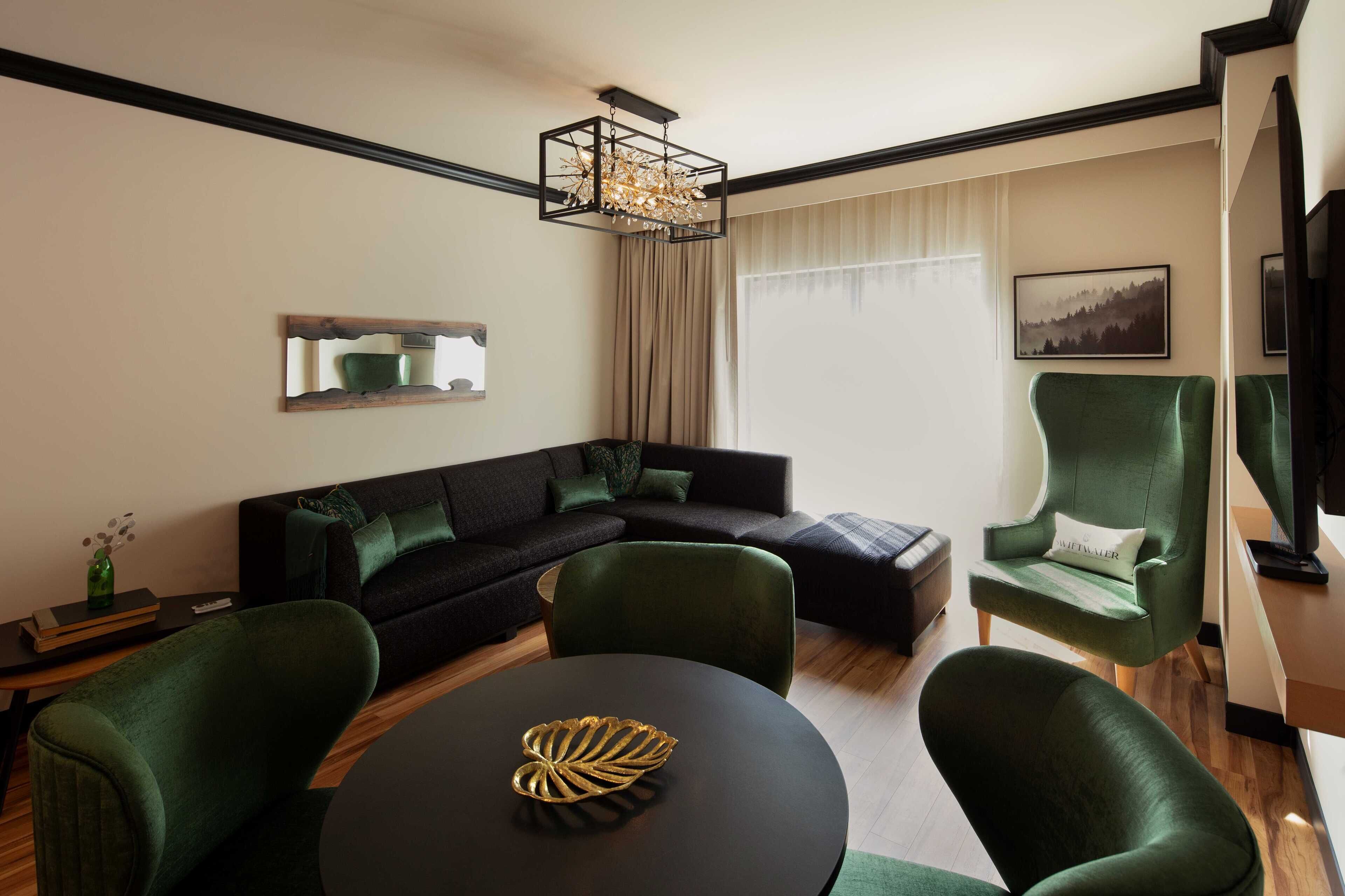 A modern living room with a sectional sofa, a round table with a decorative bowl, and a green armchair.