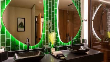 Un baño moderno con dos espejos ovalados grandes, un lavabo negro y una zona de ducha.