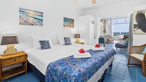 Un dormitorio con cama, mesitas de noche, ventilador de techo y obras de arte en las paredes.