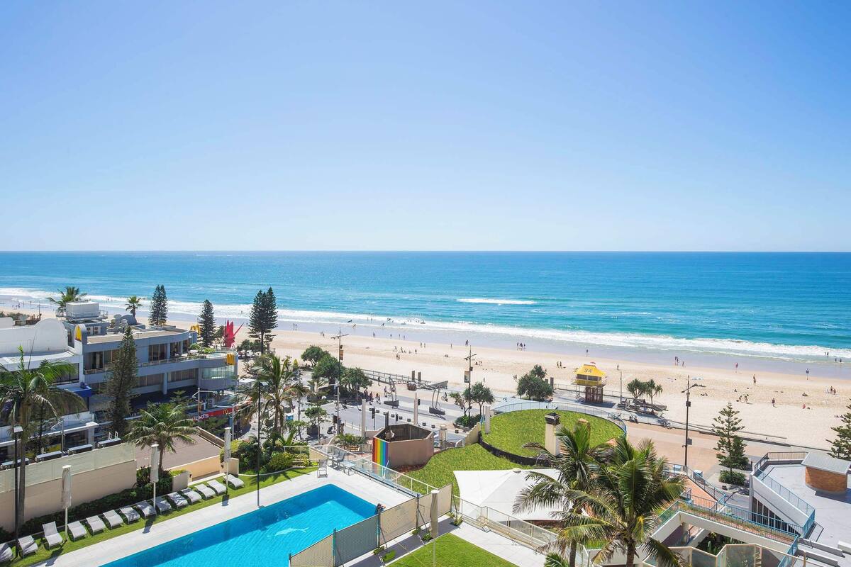 A hotel with a pool, beach view, and palm trees.