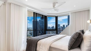 Ein modernes Schlafzimmer mit Blick auf die Stadt, einem Deckenventilator und einem großen Bett mit Aussicht.