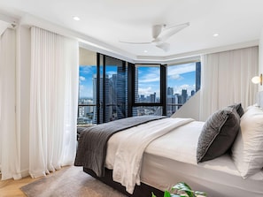 Une chambre moderne avec vue sur la ville, un ventilateur de plafond et un grand lit offrant également une vue agréable.