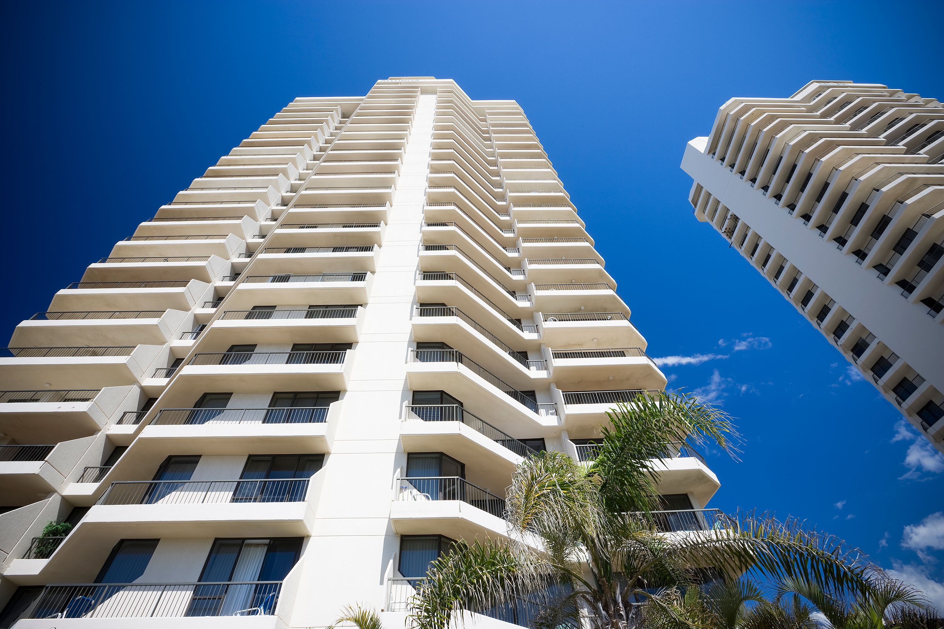 A high-rise building with multiple balconies and a clear blue sky.