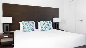 Una habitación de hotel con una cama grande, dos mesitas de noche y un armario.