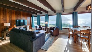 Una zona d'estar àmplia amb un televisor de pantalla plana gran, seients confortables i una taula de menjador.