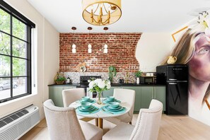A modern kitchen with a brick backsplash, a dining area with teal plates, and a black refrigerator. - The Acoma House (Denver)
