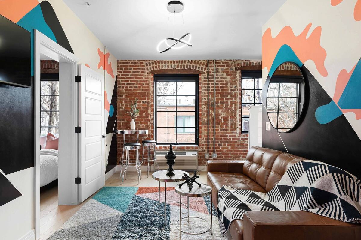 A modern living room with a leather sofa, a round table, and a patterned rug.
