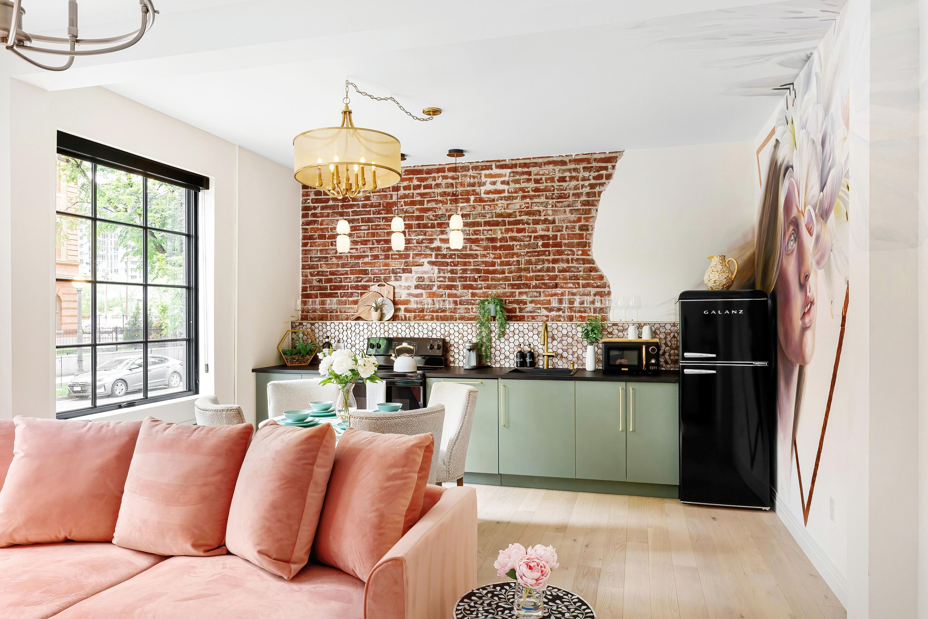 Una sala de estar moderna con sofá, comedor con mesa y sillas, cocina con salpicadero de ladrillo y refrigerador.