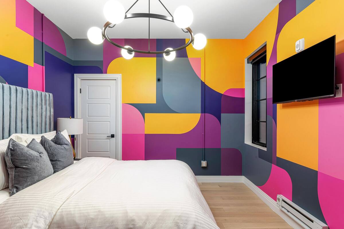 A bedroom with a bed, a TV mounted on the wall, and a door.