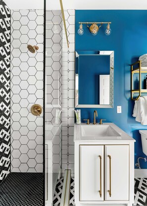 A bathroom with a white sink, gold fixtures, and a blue accent wall. - The Acoma House (Denver)