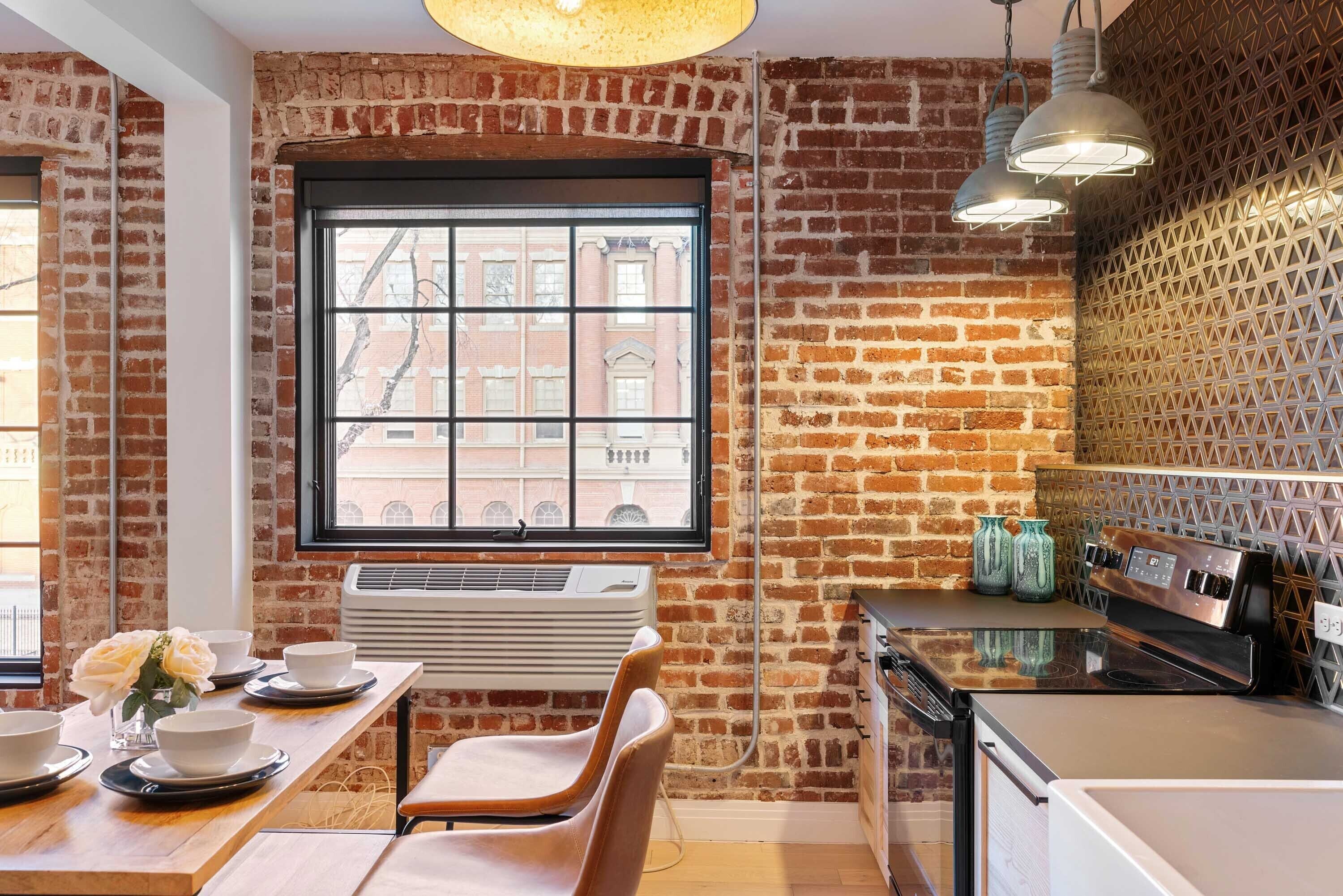Una cocina con paredes de ladrillo, una ventana y electrodomésticos modernos.