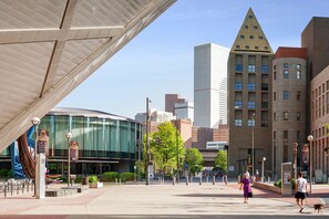 A modern urban plaza with a glass building, a triangular skyscraper, and a curved structure. - The Acoma House (Denver)